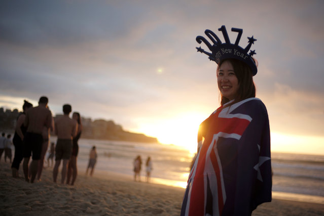 A beachgoers drapes herself in the Australian flag and wears 2017 headwear on Sydney's Bondi Beach to welcome the first sunrise of the new year in Australia's largest city, January 1, 2017. (Photo by Jason Reed/Reuters)