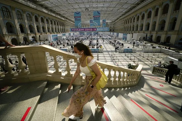 A woman climbs the stairs to queue for a COVID-19 vaccine at a vaccination center in Gostiny Dvor, a huge exhibition center, in Moscow, Russia, Tuesday, July 13, 2021. The banner, center, reads “We will defeat COVID-19 together!”. Russia gave Sputnik V regulatory approval in August 2020, raising criticism at home and abroad because it had only been tested on a few dozen people at the time. (Photo by Alexander Zemlianichenko/AP Photo)