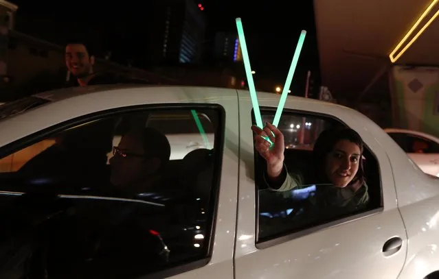 A woman in a car flashes the “V for Victory” sign with neon lights as people celebrate on Valiasr street in northern Tehran on April 2, 2015, after the announcement of an agreement on Iran nuclear talks. Iran and global powers sealed a deal on April 2 on plans to curb Tehran's chances for getting a nuclear bomb, laying the ground for a new relationship between the Islamic republic and the West. (Photo by Atta Kenare/AFP Photo)
