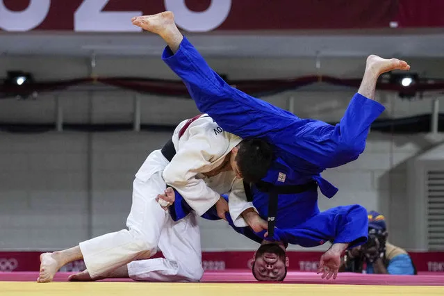 Somon Makhmadbekov, of Tajikistan, left, and Ahmad Alikaj, of the Refugee Olympic Team, compete during their men's 73kg elimination round of the judo match, at the 2020 Summer Olympics in Tokyo, Japan, Monday, July 26, 2021. (Photo by Vincent Thian/AP Photo)