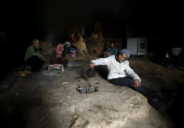 A Palestinian boy pours tea as he sits with his family inside a cave they live in, during a snow storm in West Bank village of Mufagara, south of Hebron January 27, 2016. (Photo by Mussa Qawasma/Reuters)