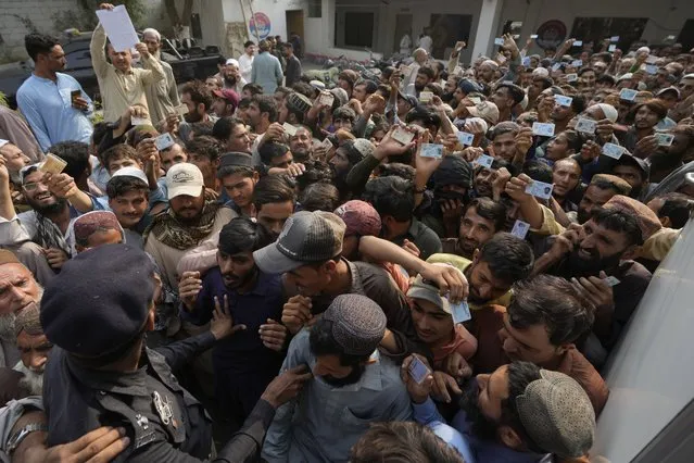 Police officers try to control immigrants, mostly Afghans, gather to verify their data at a counter of Pakistan's National Database and Registration Authority, in Karachi, Pakistan, Tuesday, November 7, 2023. Pakistan government launched a crackdown on migrants living in the country illegally as a part of the new measure which mainly target all undocumented or unregistered foreigners. (Photo by Fareed Khan/AP Photo)