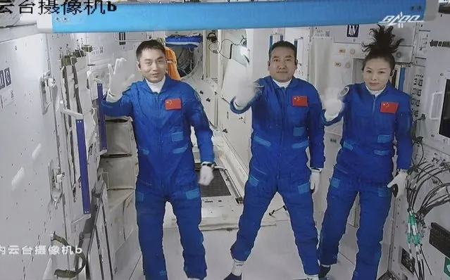 In this photo released by Xinhua News Agency, screen image captured at Beijing Aerospace Control Center in Beijing, China, Saturday, October 16, 2021 shows three Chinese astronauts, from left, Ye Guangfu, Zhai Zhigang and Wang Yaping waving after entering the space station core module Tianhe. China's Shenzhou-13 spacecraft carrying three Chinese astronauts on Saturday docked at its space station, kicking off a record-setting six-month stay as the country moves toward completing the new orbiting outpost. Chinese characters,  left, read “Platform Camera B”. (Photo by Tian Dingyu/Xinhua via AP Photo)
