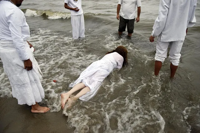 A woman lies face down in the water during a ritual honoring the African sea goddess Yemanja, in Montevideo, Uruguay, Thursday, February 2, 2017. Thousands of worshippers come to the beach on Yemanja's feast day, bearing candles, flowers, perfumes and fruit to show their gratitude for her blessings. The celebration coincides with the Roman Catholic feast day of the Virgin of Candelaria, marked Feb. 2. (Photo by Matilde Campodonico/AP Photo)