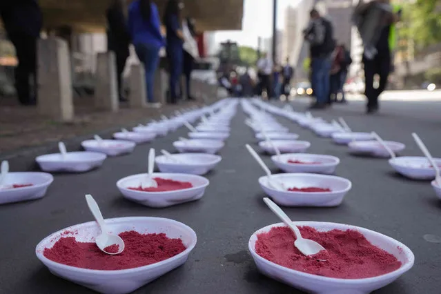 Plates of filled with red sand, representing lunchboxes, sit in a line, after being placed by activists from the Rio de Paz organization to protest the death of 19-year-old Gabriel Hoytil Araujo, killed during a police operation the previous week in Sao Paulo, Brazil, Tuesday, October 26, 2021. According to activists and the local media, Araujo was allegedly shot to death by a police officer who mistook the lunchbox he was holding for a gun during an operation against drug traffickers. (Photo by Andre Penner/AP Photo)