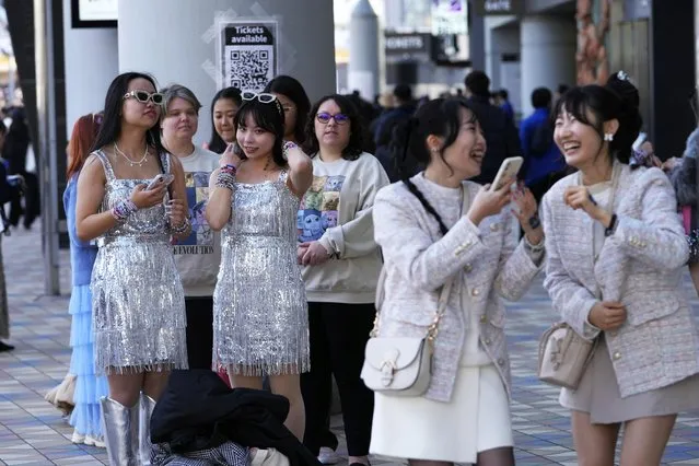 People wait in line near a poster to take their pictures with, as others, right, react to their selfie before Taylor Swift's concert at Tokyo Dome in Tokyo, Saturday, February 10, 2024. (Photo by Hiro Komae/AP Photo)