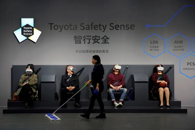 A cleaner walks past visitors wearing virtual reality (VR) goggles at a booth for Toyota Safety Sense during the media day for the Shanghai auto show in Shanghai, China April 16, 2019. (Photo by Aly Song/Reuters)