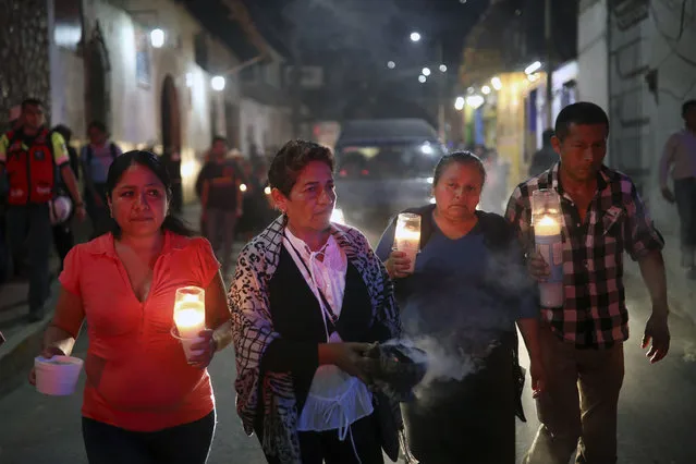 Mourners carry candles as they walk with the hearse bringing the body of Maricela Vallejo, the slain 27-year-old mayor of Mixtla de Altamirano, to her aunt's house for a wake in Zongolica, Veracruz state, Mexico, Thursday, April 25, 2019. Vallejo, her husband, and a driver were assassinated Thursday by multiple gunmen as they drove along a highway. (Photo by Felix Marquez/AP Photo)
