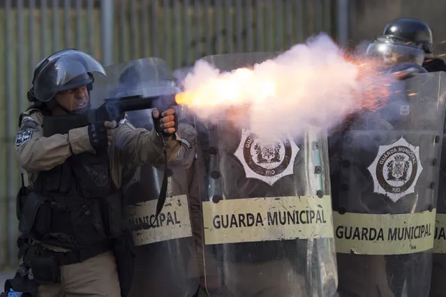 A municipal guard fires tear gas at demonstrators during a protest against the state government in Rio de Janeiro, Brazil, Monday, February 20, 2017. The protesters are denouncing a proposal to privatize the state's water and sewage company. (Photo by Leo Correa/AP Photo)