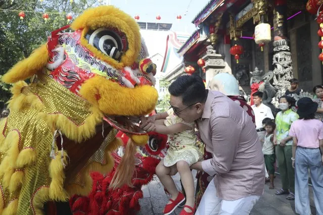 Local Chinese present a red envelop, or hongbao, to lion dance performers during a cerebration to mark the Lunar New Year at Chinatown Saturday, February 10, 2024, in Yangon, Myanmar. (Photo by Thein Zaw/AP Photo)
