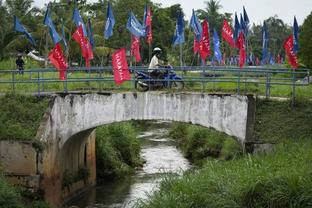 A motorcycle passing by a bridge with various of party flags at the outskirts of Melacca town, Malaysia, Saturday, November 20, 2021. Voters wearing masks are casting their ballots in a Malaysian state election that pits Prime Minister Ismail Sabri Yaakob’s Malay party against its allies in the government for the first time amid a widening rift. (Photo by Vincent Thian/AP Photo)