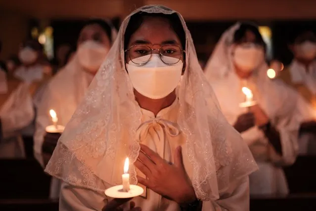 Catholic faithful hold candles during the Easter Vigil at St. Kristoforos church in Jakarta on March 30, 2024. (Photo by Yasuyoshi Chiba/AFP Photo)