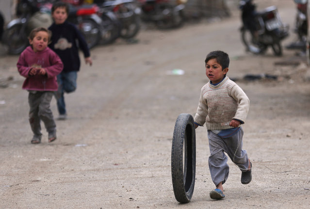 A boy pushes a tire along a street in the Syrian rebel-held town of al-Rai, Syria March 2, 2017. (Photo by Khalil Ashawi/Reuters)