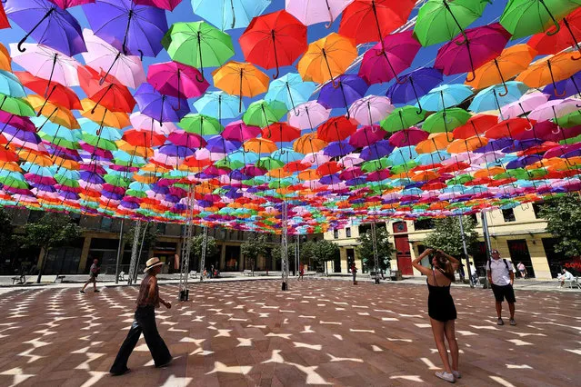 Visitors take shelter from the heat under “Umbrella Sky Project” installation by Portuguese artist Patricia Cunha in Aix-en-Provence on June 28, 2019 as a heatwave hits France with temperatures that may exceed 45 degrees Celsius, a high never seen in mainland France. (Photo by Boris Horvat/AFP Photo)
