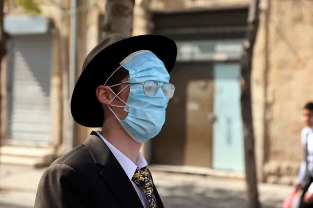 An Ultra Orthodox man wears three masks over his face while celebrating Purim amid coronavirus disease (COVID-19) restrictions in Jerusalem on February 28, 2021. (Photo by Ronen Zvulun/Reuters)
