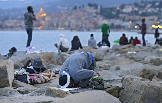 Migrant kneels in prayer, in Ventimiglia, at the Italian-French border Tuesday, June 16, 2015. Police at Italy's Mediterranean border with France forcibly removed a few dozen African migrants who have been camping out for days in hopes of continuing their journeys farther north, a violent scene Italy is using to show that Europe needs to do something about the migrant crisis. (AP Photo/Lionel Cironneau)