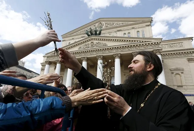A clergyman distributes p*ssy willow among Orthodox believers during Palm Sunday celebrations in front of the Bolshoi Theatre in central Moscow, Russia, April 24, 2016. (Photo by Sergei Karpukhin/Reuters)