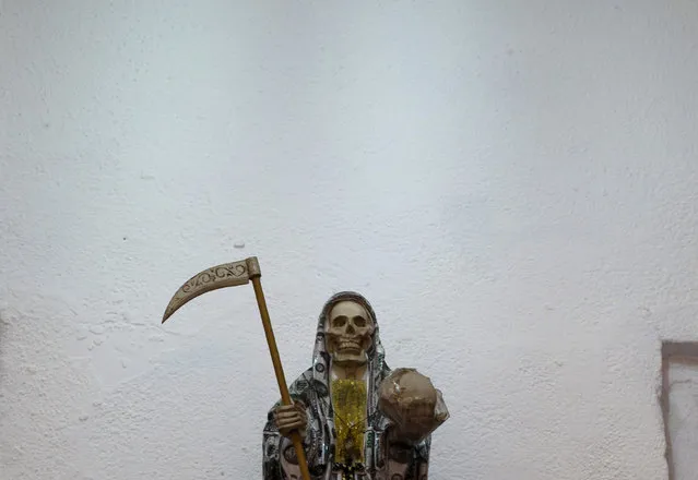 In this February 26, 2017 photo, a statue of the Death Saint or “Santa Muerte” wears a cloak of U.S. dollar bills inside Mercy Church on the edge of Mexico City's Tepito neighborhood. Usually the vestments of the folk saint are differently colored robes, but it is also common for her to be dressed as a bride or in nun's garments. (Photo by Marco Ugarte/AP Photo)