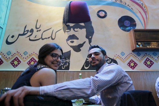 People pose for a photograph at a newly opened pub in front of a stencil of Syrian actor Duraid Lahham in Damascus, Syria, March 24, 2016. The writing on the wall reads: “Cheers to homeland”. In Damascus's Old City, just a mile from the battered frontline between government and rebel-held territory, young Syrians smoke, drink beer or soft drinks, and talk about anything but the war. (Photo by Omar Sanadiki/Reuters)