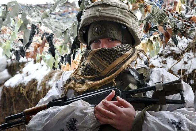 A Ukrainian serviceman looks at a photographer standing in a trench at the frontline with Russia-backed separatists in Verkhnotoretske village, Yasynuvata district in Donetsk region, eastern Ukraine, Saturday, January 29, 2022. Russia has launched military drills involving motorized infantry and artillery units in southwestern Russia, warplanes in Kaliningrad on the Baltic Sea, and dozens of warships in the Black Sea and the Arctic. (Photo by Andriy Andriyenko/AP Photo)