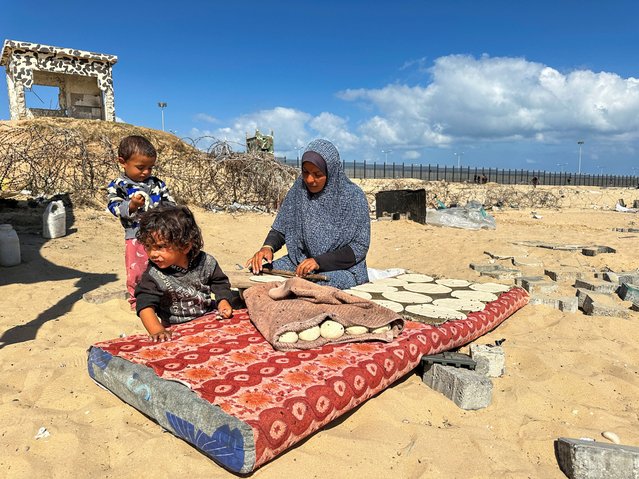 A woman prepares food next to children, as displaced Palestinians take shelter at the border with Egypt, during an Israeli military operation, in Rafah in the southern Gaza Strip, on May 29, 2024. (Photo by Doaa Rouqa/Reuters)