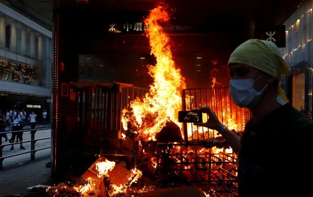 A protester films a fire at the entrance of MTR Central Station in Hong Kong, China on September 8, 2019. (Photo by Anushree Fadnavis/Reuters)