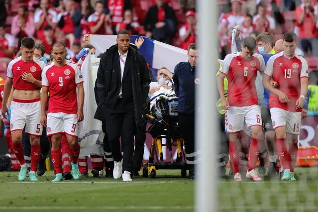 Denmark's players escort Denmark's midfielder Christian Eriksen (C) as he is evacuated after collapsing on the pitch during the UEFA EURO 2020 Group B football match between Denmark and Finland at the Parken Stadium in Copenhagen on June 12, 2021. (Photo by Friedemann Vogel/AFP Photo)