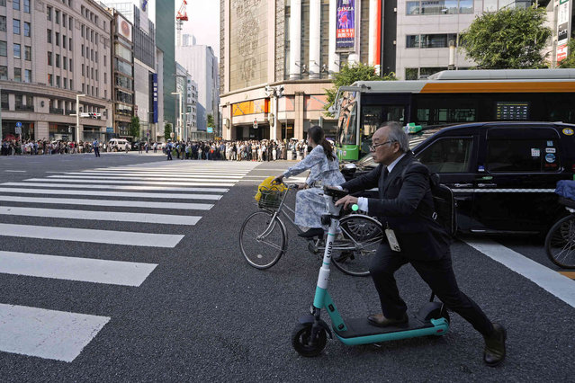 A man on an electric scooter crosses an intersection in central Tokyo, Friday, June 7, 2024 in Tokyo. (Photo by Shuji Kajiyama/AP Photo)