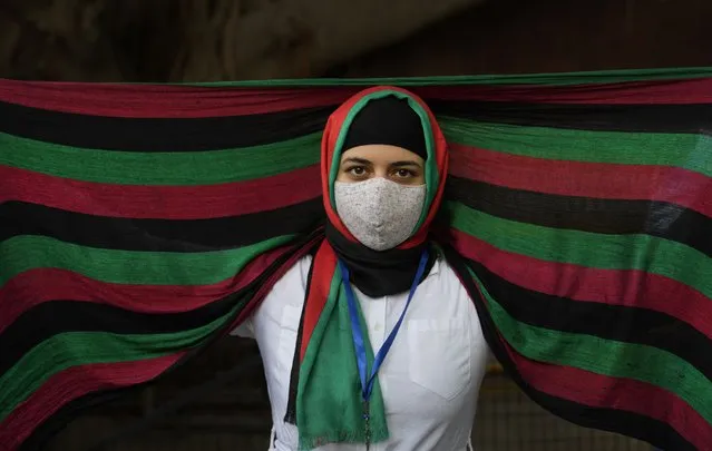 An Afghan refugee wearing a scarf in the colours of the national flag of Afghanistan participates in a protest outside the UNHCR office (United Nation High Commissioner for Refugees) in New Delhi, India, Monday, August 23, 2021. Hundreds of Afghans living in India gathered to protest against the Taliban takeover of Afghanistan and also demanded to be given refugee status in India. (Photo by Manish Swarup/AP Photo)