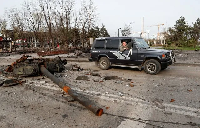 A passenger of a car speaks near the turret of a tank, which was destroyed during Ukraine-Russia conflict in the southern port city of Mariupol, Ukraine April 17, 2022. (Photo by Alexander Ermochenko/Reuters)