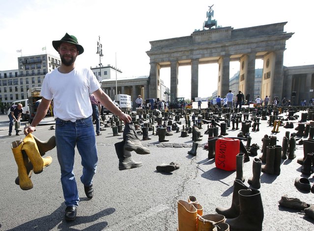 A farmer spreads out Wellington boots during a protest by German dairy farmers demanding a fair price structure for milk products in front of the Brandenburg Gate in Berlin, Germany May 30, 2016. (Photo by Fabrizio Bensch/Reuters)