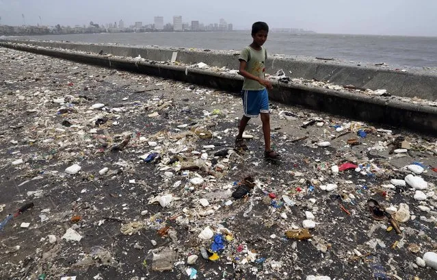 A boy walks through the Arabian Sea coast after tidal waves receded filling the shore with garbage in Mumbai, India, Thursday, June 12, 2014. (Photo by Rajanish Kakade/AP Photo)