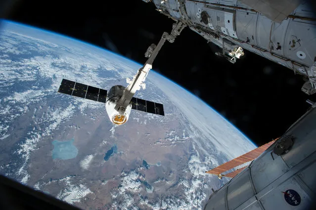 In this Friday, April 17, 2015 file photo, the Canadarm 2 reaches out to capture the SpaceX Dragon cargo spacecraft for docking to the International Space Station. Americans haven't rocketed into orbit from their home turf since NASA's last shuttle flight in 2011. SpaceX and Boeing expect to resume human launches from Cape Canaveral in another year or two. (Photo by AP Photo/NASA)