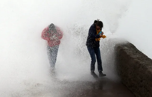 People escape a wave from the Atlantic Ocean, in Biarritz, southwestern France, Sunday, December 22, 2019. Most of the French regions are on alert for violent storms and high winds. (Photo by Bob Edme/AP Photo)