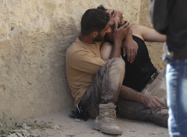 A civil defence member comforts his comrade at a site hit by airstrike in the rebel-controlled area of Maaret al-Numan town in Idlib province, Syria, June 12, 2016. (Photo by Khalil Ashawi/Reuters)
