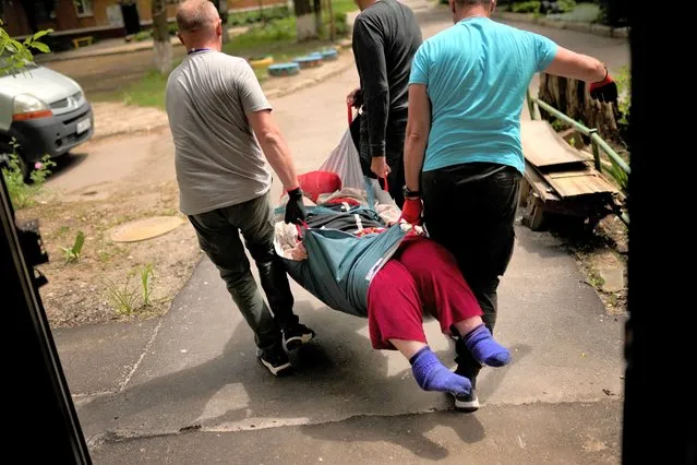 A woman is carried from her home in an evacuation by volunteers of Vostok SOS charitable organisation in Kramatorsk, eastern Ukraine, Thursday, May 26, 2022. Residents in villages and towns near the front line continue to flee as fighting rages in eastern Ukraine. (Photo by Francisco Seco/AP Photo)