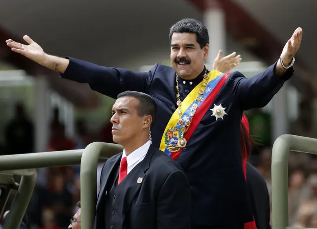 Venezuela's President Nicolas Maduro holds out his arms as arrives to attend a military parade commemorating the country's Independence Day in Caracas, Venezuela, Wednesday, July 5, 2017. Venezuela is marking 206 years of their declaration of independence from Spain. (Photo by Ariana Cubillos/AP Photos)