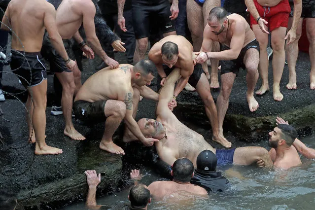 Swimmers pull a Greek Orthodox faithful who lost consciousness  out of the water as he swam with others to retrieve a wooden crucifix during the Epiphany ceremony in Istanbul, Monday, January 6, 2020. Media were told the man is alive and recovering at a hospital. More than a dozen Orthodox men raced to retrieve the cross which was thrown into the waters by Ecumenical Patriarch Bartholomew I, the spiritual leader of the world's Orthodox Christians. (Photo by Lefteris Pitarakis/AP Photo)