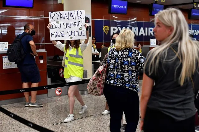 A woman holds a placard reading “Ryanair, low salaries made simple” as she protests at the Terminal 2 of El Prat airport in Barcelona on June 24, 2022. Trade unions representing Ryanair cabin crew in Belgium, France, Italy, Portugal and Spain have called for strikes this coming weekend, while easyJet's operations in Spain face a nine-day strike next month. (Photo by Pau Barrena/AFP Photo)