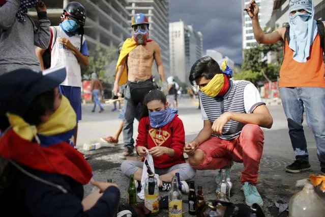 Anti-government demonstrators prepare homemade petrol bombs that will be used against Venezuelan Bolivarian National Police, during a protest against the installation of a constitutional assembly in Caracas, Venezuela, Friday, August 4, 2017. Defying criticism from Washington to the Vatican, Venezuela's ruling party on Friday installed a new super assembly that supporters promise will pacify the country and critics fear will be a tool for imposing dictatorship. (Photo by Ariana Cubillos/AP Photo)