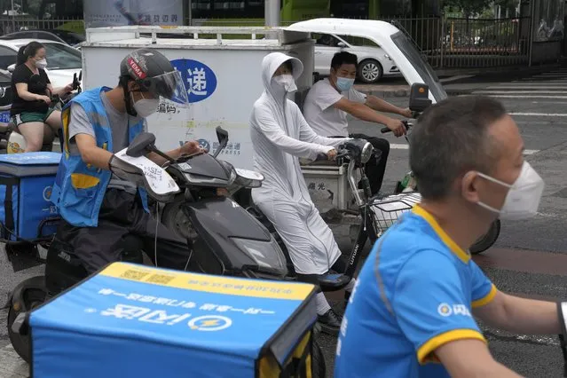 Delivery drivers wearing masks go about their work, Monday, June 27, 2022, in Beijing. (Photo by Ng Han Guan/AP Photo)