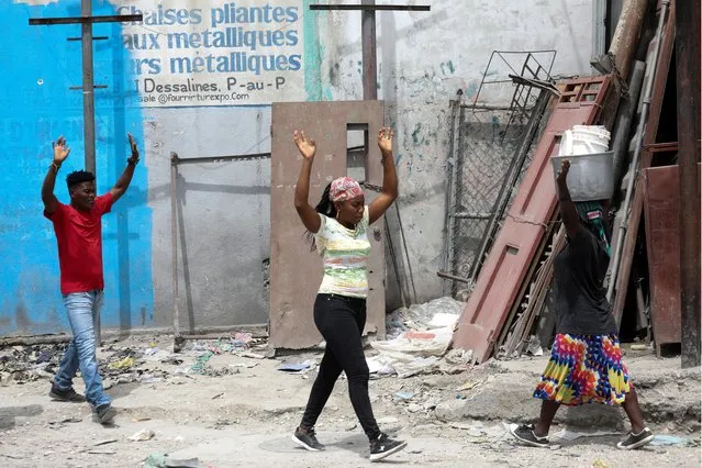Residents raise their arms as they flee their homes due to ongoing gun battles between rival gangs, in Port-au-Prince, Haiti on May 2, 2022. (Photo by Ralph Tedy Erol/Reuters)
