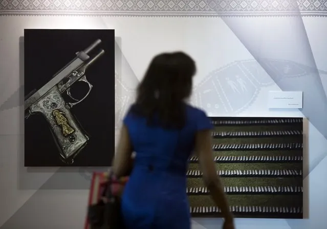 A woman passes in front of pictures of a gun and bullets during the Arms Trade Treaty meeting in Cancun August 24, 2015. Signatories of the treaty, aimed at regulating the international arms trade, should agree a number of key steps for its implementation at a conference this week, host nation Mexico said on Sunday. (Photo by Victor Ruiz Garcia/Reuters)
