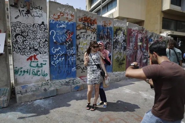Lebanese women have their picture taken in front a concrete wall installed by authorities near the main Lebanese government building, in downtown Beirut, Lebanon, Tuesday, August 25, 2015. Anticipating more protests, authorities installed a concrete wall near the main Lebanese government building, site of the largest protests. (Photo by Hassan Ammar/AP Photo)