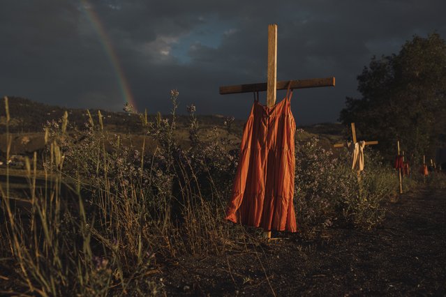This image provided by World Press Photo which won the World Press Photo Of The Year award by Amber Bracken for The New York Times, titled Kamloops Residential School, shows Red dresses hung on crosses along a roadside commemorate children who died at the Kamloops Indian Residential School, an institution created to assimilate Indigenous children, following the detection of as many as 215 unmarked graves, Kamloops, British Columbia, 19 June 2021. (Photo by Amber Bracken for The New York Times/World Press Photo via AP Photo)