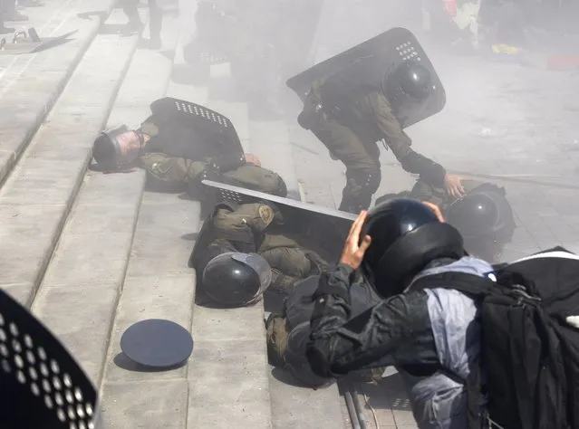 Police officers help wounded colleagues during clashes with activists of few radical Ukrainian parties in front of the parliament in Kiev on August 31, 2015. At least 20 were wounded in clashes outside parliament in Kiev on Monday after lawmakers gave initial approval to constitutional changes granting more autonomy to pro-Russian separatists in eastern Ukraine. (Photo by Yuriy Kirnichny/AFP Photo)