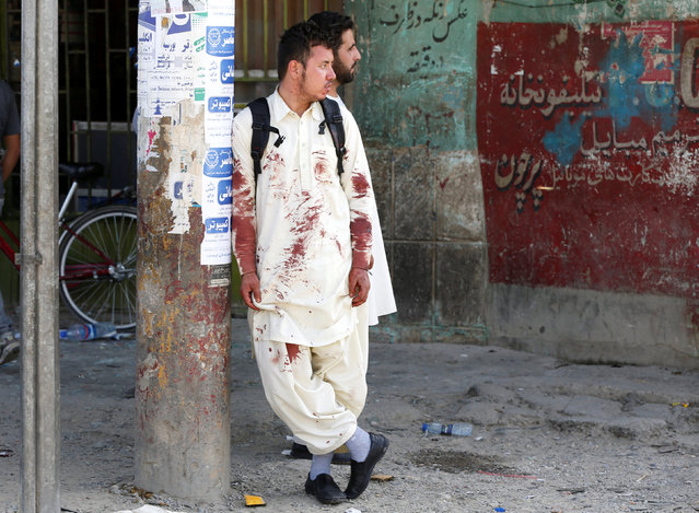 An Afghan man with bloodstained clothes stands at the side of blast after a suicide attack in Kabul, Afghanistan July 23, 2016. (Photo by Omar Sobhani/Reuters)