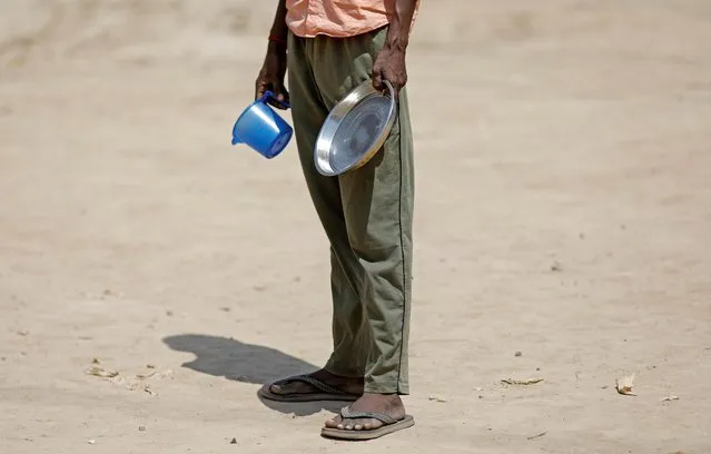 A daily wage labourer stands in a queue for free food at a construction site where activity has been halted due to 21-day nationwide lockdown to slow the spreading of the coronavirus disease (COVID-19), in New Delhi, India, April 10, 2020. (Photo by Adnan Abidi/Reuters)