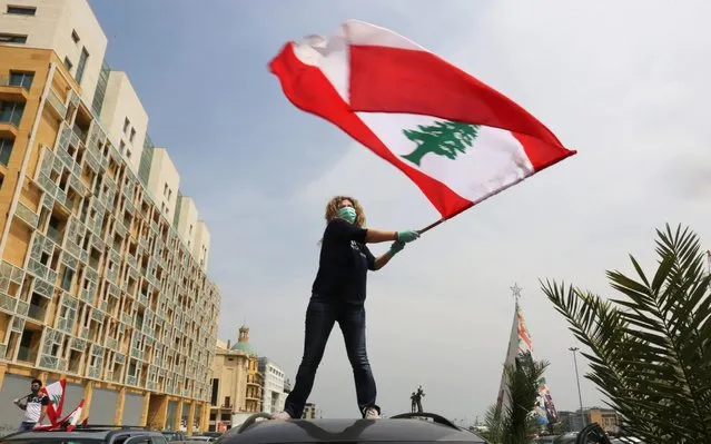 An anti-government demonstrator holds a Lebanese flag as she stands on top of her car, during a countrywide lockdown to combat the spread of the coronavirus disease (COVID-19), in Beirut, Lebanon on April 21, 2020. (Photo by Aziz Taher/Reuters)