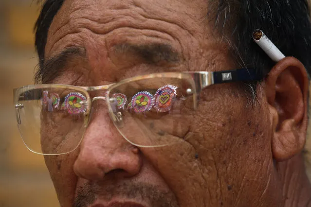 Wreathes are reflected on the glasses of a resident during a funeral ceremony for victim of floods in Xingtai, Hebei Province, China, July 24, 2016. (Photo by Reuters/Stringer)